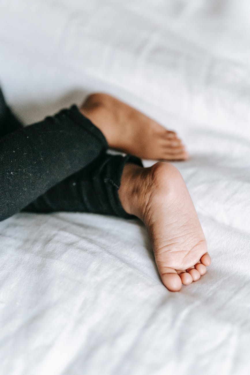 anonymous black child lying on bed at home